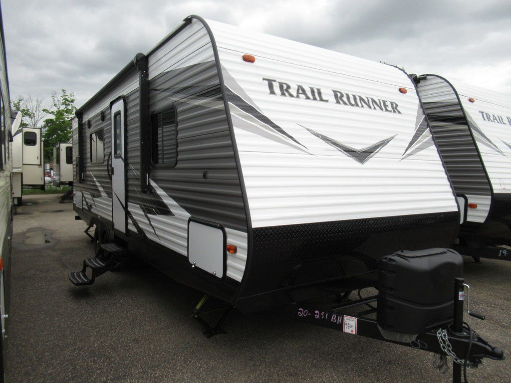 White & gray 2020 Heartland® Trail Runner® RV on a selling lot surrounded by other trailers during a cloudy day.